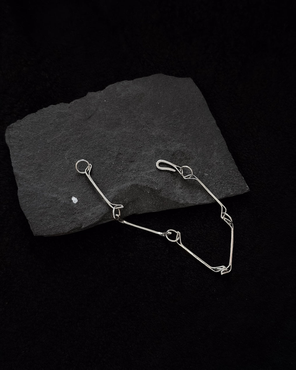 Minimalist sterling silver bracelet lying on a stone, sculptural design inspired by a horse jawbone