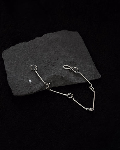 Minimalist sterling silver bracelet lying on a stone, sculptural design inspired by a horse jawbone