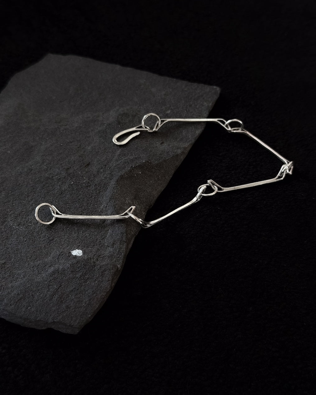 Minimalist sterling silver bracelet lying on a stone, sculptural design inspired by a horse jawbone