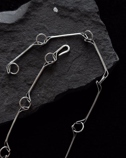Minimalist sterling silver necklace lying on a stone, sculptural design inspired by a horse jawbone